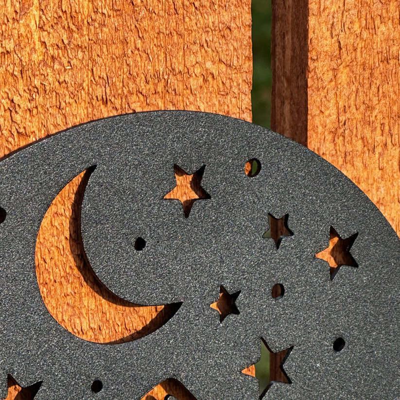 A close-up of a black metal sign featuring a crescent moon and star cutouts, highlighting the diverse color and size options available for custom signs. The textured black finish contrasts beautifully against a warm wooden background, showcasing one of the five timeless color choices. This image emphasizes the versatility of sign sizes and colors, catering to a range of styles from bold to subtle, ensuring the perfect fit for any space, whether indoors or outdoors.