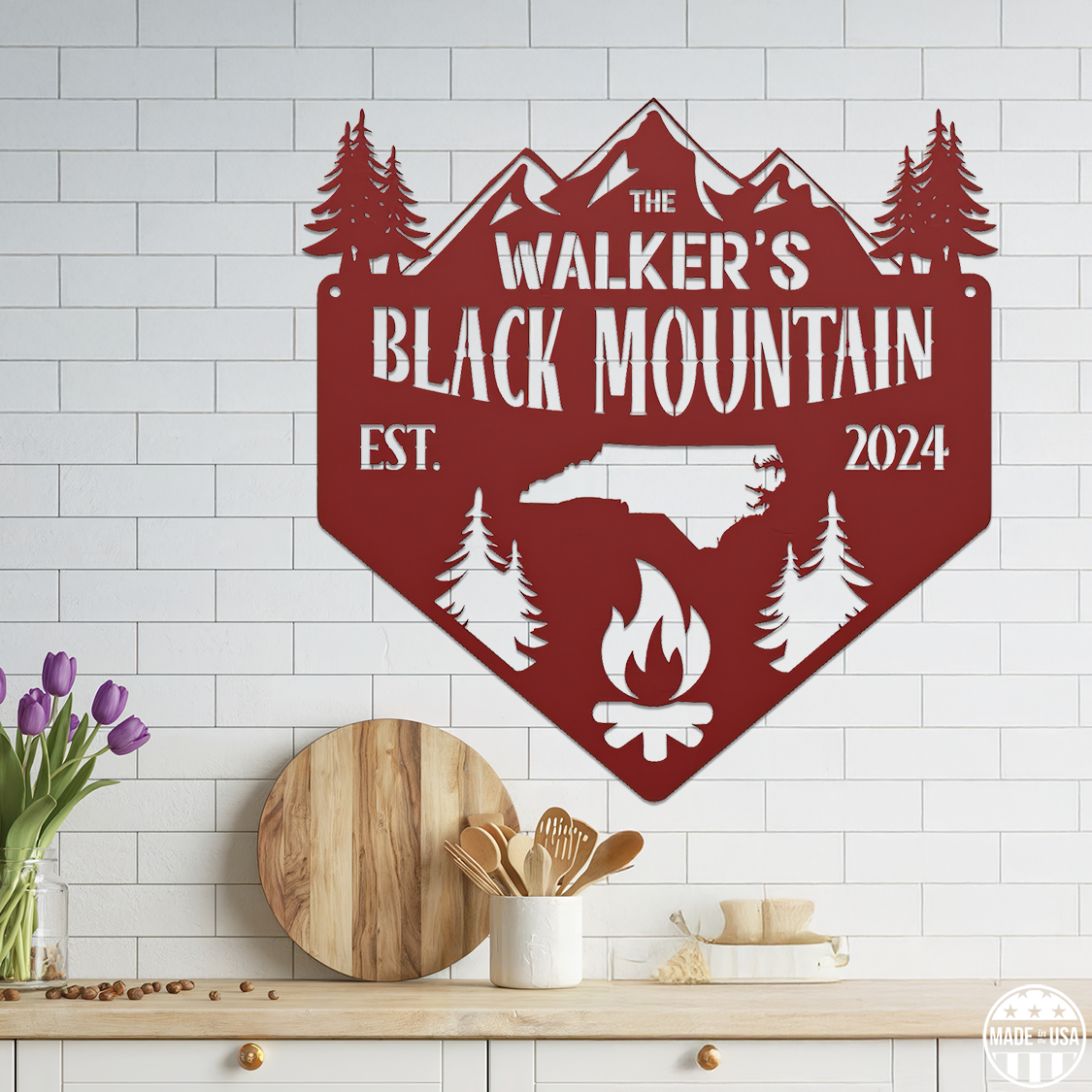 A customizable red metal sign mounted on a tiled wall, featuring kitchen elements and a campfire with text that reads 'Black Mountain Est. 2024.'