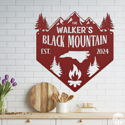 A customizable red metal sign mounted on a tiled wall, featuring kitchen elements and a campfire with text that reads 'Black Mountain Est. 2024.'